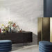 Living room featuring Petra Avorio Ivory stone marble effect porcelain wall tiles in a 60cm x 120cm format, showcasing soft ivory, pearl white and light grey veining inspired by natural stone, paired with colourful glass vases, fresh floral arrangements and contemporary styling to create a bright, elegant interior.