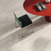 Close-up of Petra Beige stone marble effect porcelain wall and floor tiles in a 30cm x 60cm format, showcasing warm beige, ivory and soft cream veining inspired by natural stone, paired with a contemporary red statement table, green upholstered chair and elegant modern furnishings for a sophisticated interior.