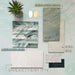 Moodboard featuring Petra Verde Green stone marble effect porcelain tiles, paired with Petra Beige stone effect tiles, Crete Fluted Jade marble effect feature tiles and Riad Blanco Neutra Stone porcelain tiles. The scheme combines soft green, warm beige and crisp white tones with brushed brass accents, natural textures and dark wood finishes to create a calming, contemporary bathroom inspired by natural stone.