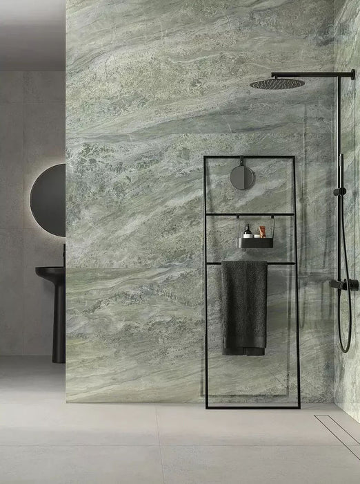 Bathroom featuring Petra Verde Green stone marble effect porcelain wall tiles in a 30cm x 60cm format, showcasing flowing green, sage and soft grey veining inspired by natural stone, paired with a walk-in shower, black framed shower screen, matte black brassware and minimalist fittings for a contemporary spa-inspired bathroom.
