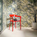 Bathroom featuring Plant Life Light Decor 60x120cm botanical-style wall tiles, showcasing a soft tropical leaf design in green, blue and beige tones, paired with a bold red chair, large indoor plant and minimalist décor.