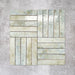 Product display of Pottery Brick Agave Green 5x25cm glossy wall tiles in soft green and sage tones, arranged in a basketweave layout with handcrafted edges and subtle tonal variation against a textured concrete-style backdrop.