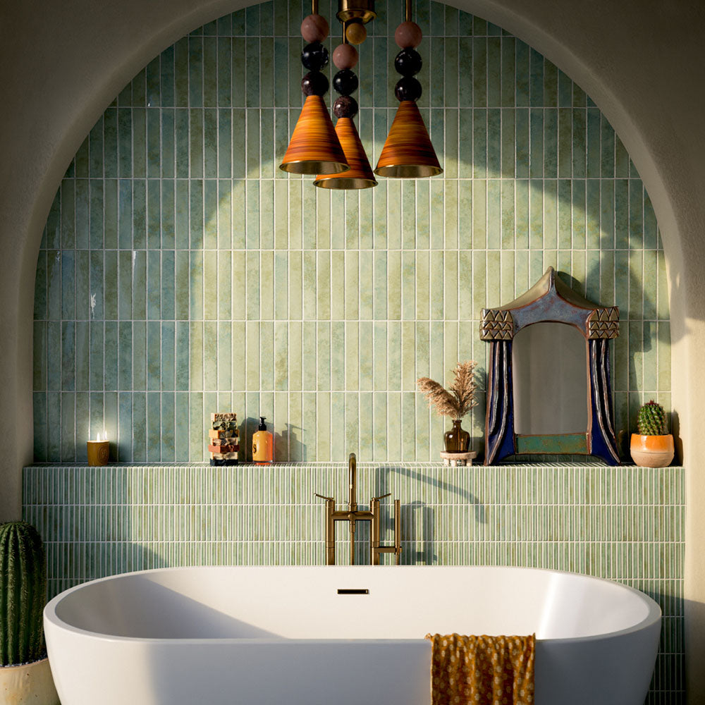 Bathroom featuring Pottery Agave Green 5x25cm glossy brick wall tiles with tonal variation, paired with striped tile detailing and brushed brass fixtures for a warm, spa-inspired contemporary interior.