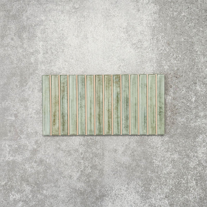 Product display of Pottery Decor Agave Green 12.5x25cm ceramic wall tiles in soft green tones, featuring a linear fluted design, handcrafted glossy finish and subtle tonal variation for textured contemporary interiors.