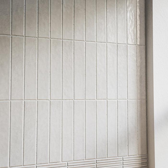 Close-up of Pottery Brick Blanco 5 × 25cm ceramic wall tiles, featuring soft white tones, subtle tonal variation, and a glossy handcrafted finish in a slim brick format for a refined contemporary wall design.