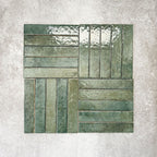 Product display of Pottery Brick Forest Green 5x25cm glossy wall tiles in deep green tones, arranged in a basketweave layout with handcrafted edges and rich tonal variation against a textured concrete-style backdrop.