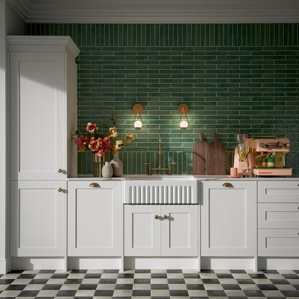 Kitchen featuring Pottery Forest Green 5x25cm glossy brick wall tiles, styled with cream shaker cabinetry, brass fixtures, a Belfast sink, and chequerboard floor tiles for a warm, vintage-inspired interior.