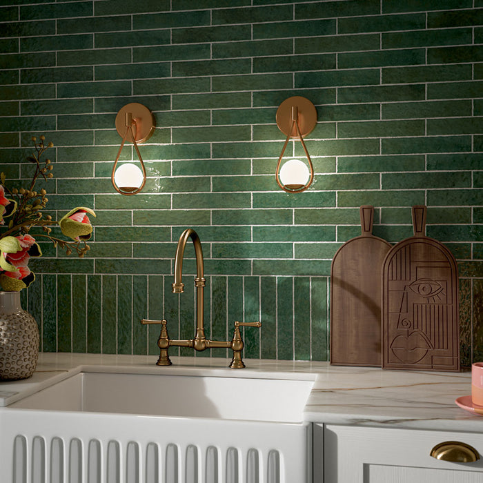 Kitchen featuring Pottery Forest Green 5x25cm glossy brick wall tiles, styled with cream shaker cabinetry, brass fixtures, a Belfast sink, and chequerboard floor tiles for a warm, vintage-inspired interior.