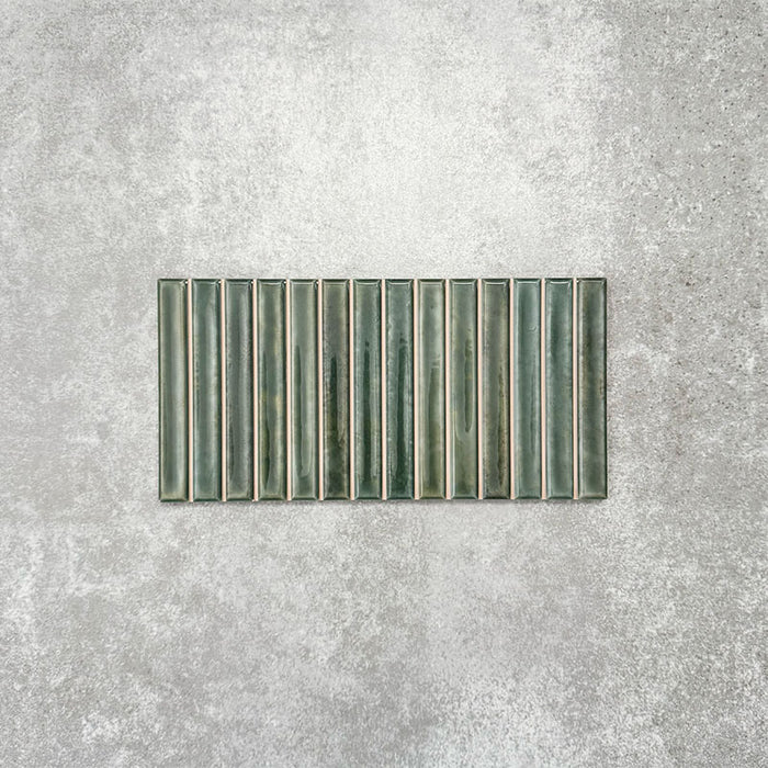 Product display of Pottery Decor Forest Green 12.5x25cm ceramic wall tiles in deep green tones, featuring a linear fluted design, handcrafted glossy finish and subtle tonal variation for textured contemporary interiors.