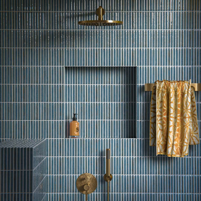 Shower interior featuring Pottery Decor Prussian wall tiles 12.5 × 25cm, laid in a vertical stacked layout to emphasise height and rhythm. The deep blue glazed finish with subtle tonal variation adds richness and depth, complemented by a built-in niche, ribbed tiled bench, and brushed brass fittings for a refined, contemporary look.