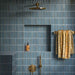 Shower interior featuring Pottery Decor Prussian wall tiles 12.5 × 25cm, laid in a vertical stacked layout to emphasise height and rhythm. The deep blue glazed finish with subtle tonal variation adds richness and depth, complemented by a built-in niche, ribbed tiled bench, and brushed brass fittings for a refined, contemporary look.