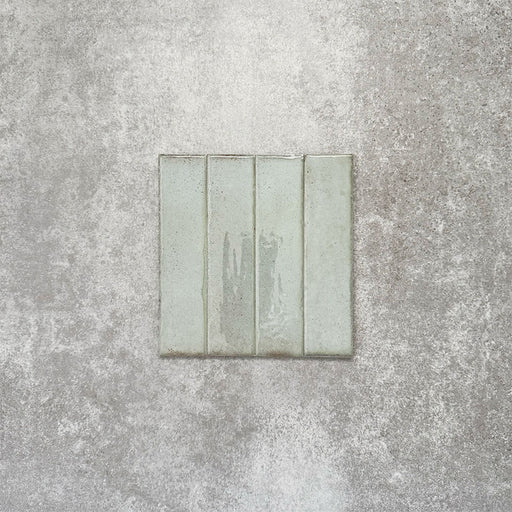 Product image of Puzzle Breeze Green Brick Rectified 5x20cm wall and floor tiles, featuring a glossy pale green finish with subtle tonal variation and softly aged edges, displayed to highlight the tile's handcrafted character.