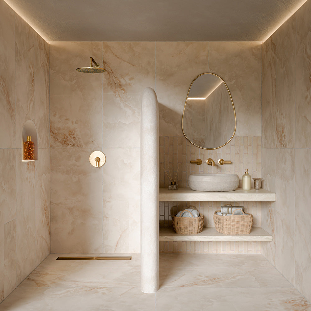 Bathroom featuring Puzzle Cream Brick Rectified 5cm x 20cm wall and floor tiles, used as a basin splashback and paired with ivory onyx effect tiles, brass fittings and neutral décor.