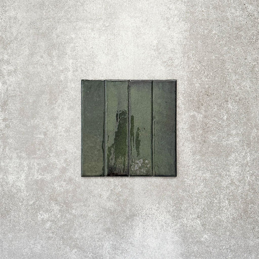 Product image of Puzzle Forest Green Brick Rectified 5x20cm wall and floor tiles, featuring a glossy deep green finish with rich tonal variation and softly aged edges, displayed to highlight the tile's handcrafted character.