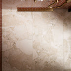 Close-up of Riad Avorio Sassi Terrazzo Stone 60cm x 120cm tiles across a shower wall, showcasing a warm ivory stone effect with varied natural-looking fragments and subtle tonal variation, paired with coral brick tiles and brass details.