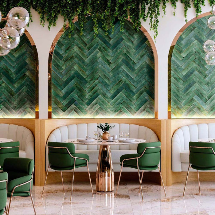 Restaurant interior featuring Allegra Green Gloss brick ceramic tiles in a 6 × 25cm format, laid in a herringbone pattern across arched feature walls, showcasing rich green tones, a glossy finish and subtle tonal variation that adds depth and elegance to the space.