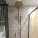 Customer bathroom featuring Riad Avorio Sassi Stone 30x60cm stone-effect wall tiles, showcasing warm ivory and beige tones with natural stone-inspired detailing, paired with brushed brass shower fittings and deep green brick tiles.