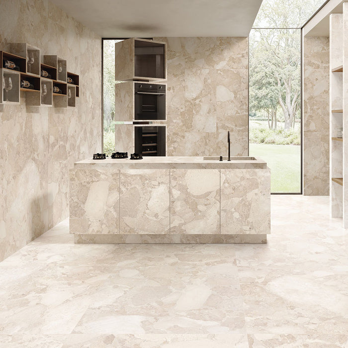 Contemporary kitchen featuring Riad Avorio Sassi Terrazzo Stone 60x120cm stone-effect wall and floor tiles, showcasing warm ivory and beige tones with natural stone-inspired detailing, paired with a matching waterfall island, integrated cabinetry and floor-to-ceiling glazing.