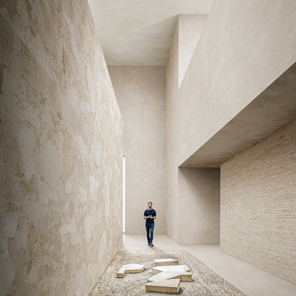 Contemporary interior featuring Riad Avorio Sassi Terrazzo Stone 60x120cm stone-effect wall and floor tiles, showcasing warm ivory and beige tones with natural stone-inspired detailing, creating a spacious architectural setting with minimalist finishes.