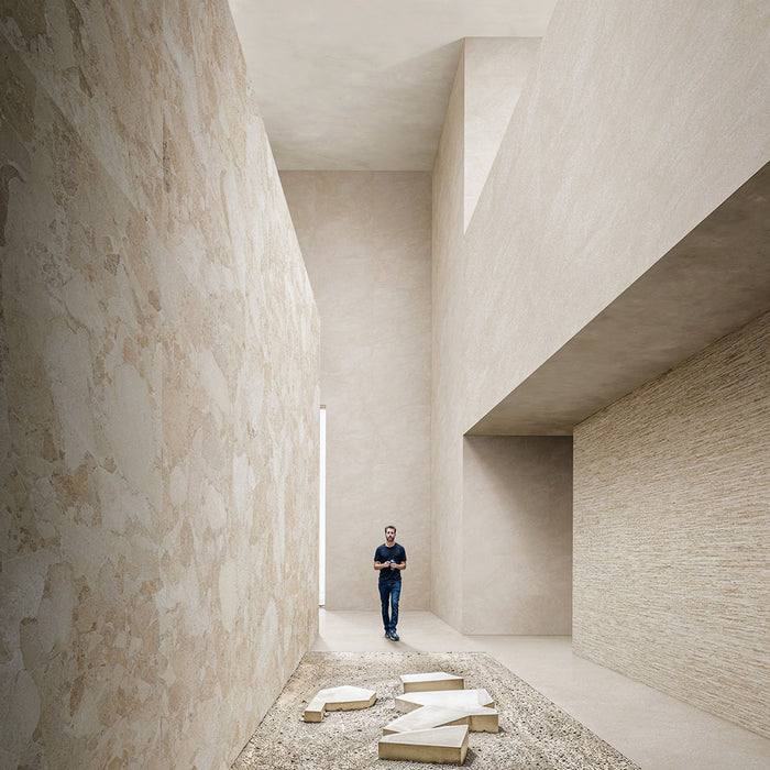 Contemporary interior featuring Riad Avorio Sassi Terrazzo Stone 60x120cm stone-effect wall and floor tiles, showcasing warm ivory and beige tones with natural stone-inspired detailing, creating a spacious architectural setting with minimalist finishes.