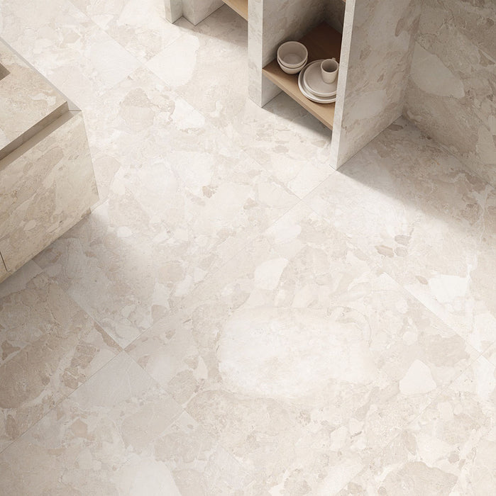 Interior featuring Riad Avorio Sassi Terrazzo Stone 60x60cm stone-effect wall and floor tiles, showcasing warm ivory and beige tones with natural stone-inspired detailing, styled with matching tiled cabinetry and light wood shelving for a contemporary finish.
