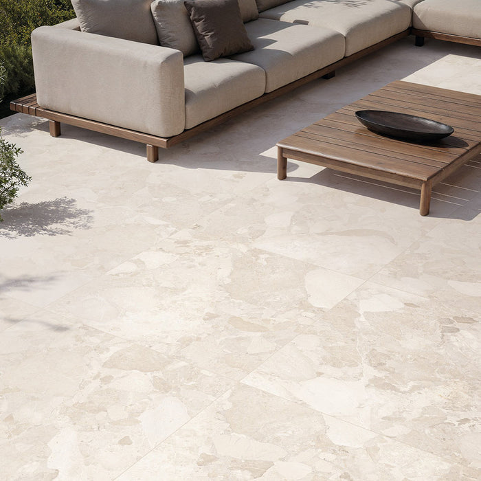 Contemporary outdoor patio featuring Riad Avorio Terrazzo 20mm 100x100cm outdoor stone-effect porcelain tile slabs, showcasing warm ivory and beige tones, paired with minimalist lounge seating, timber furniture and landscaped gardens.