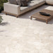 Contemporary outdoor patio featuring Riad Avorio Terrazzo 20mm 100x100cm outdoor stone-effect porcelain tile slabs, showcasing warm ivory and beige tones, paired with minimalist lounge seating, timber furniture and landscaped gardens.