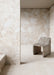 Interior featuring Riad Blanco Neutra Stone 30x60cm stone-effect wall and floor tiles, showcasing soft cream and beige tones with natural stone-inspired detailing, paired with a sculptural stone chair in a minimalist contemporary space.