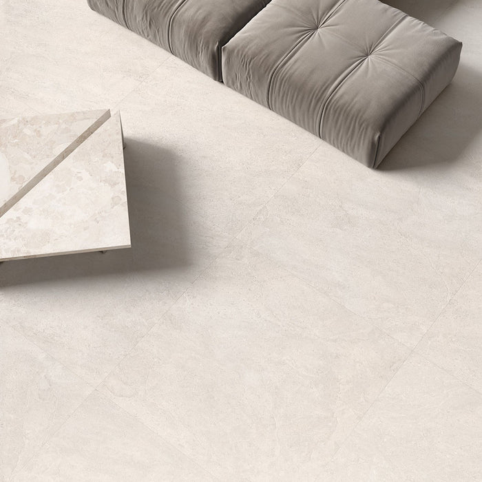 Contemporary living space featuring Riad Blanco Neutra Stone 60x60cm stone-effect wall and floor tiles, showcasing soft cream and beige tones, paired with minimalist furniture, floor-to-ceiling glazing and warm natural textures.