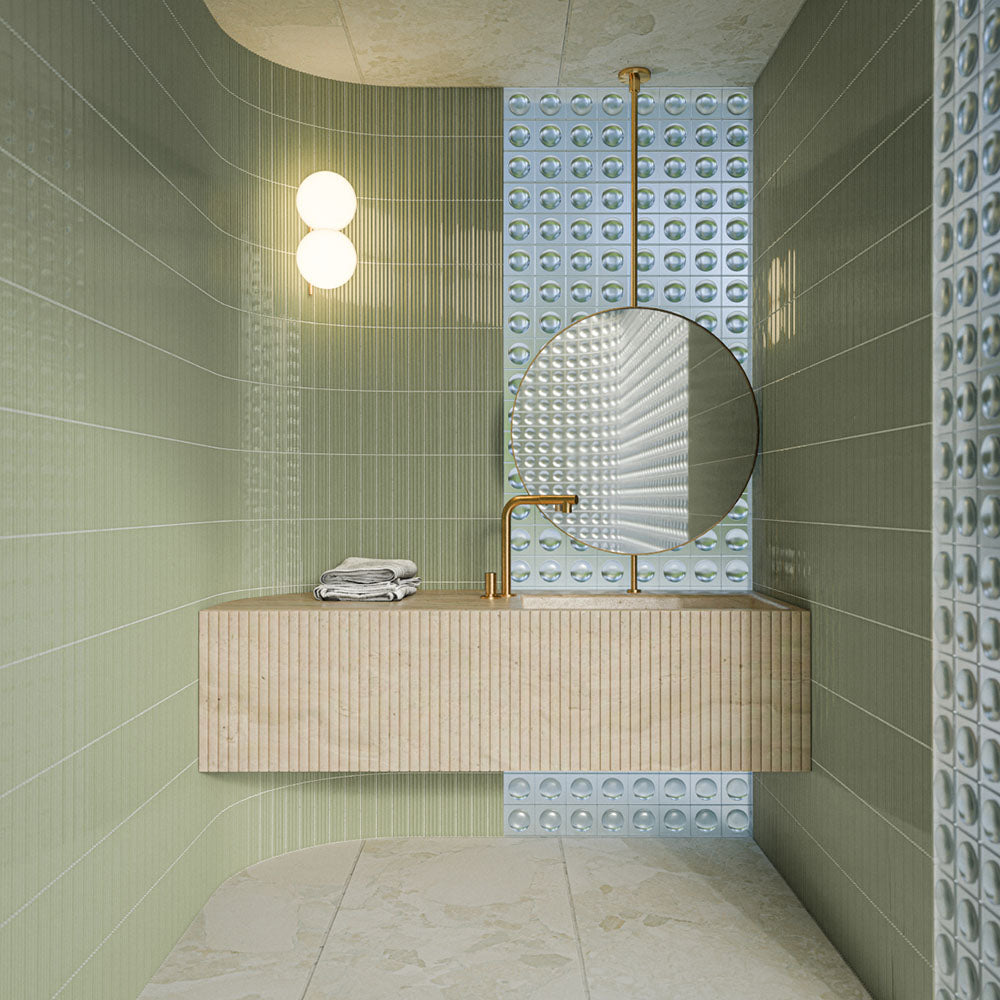 Bathroom featuring Riad Blanco Sassi Terrazzo Stone 60cm x 120cm wall and floor tiles, paired with green fluted wall tiles, a floating vanity, round mirror and brass fixtures.