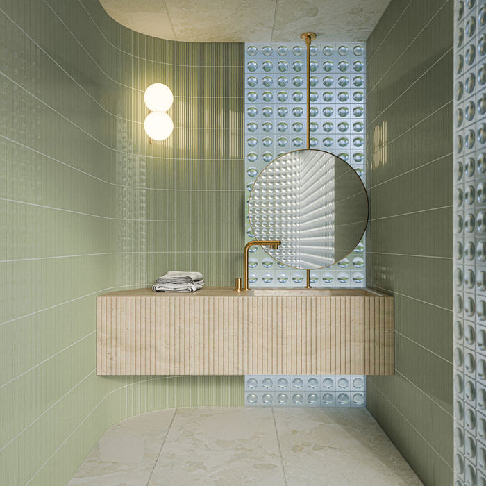 Bathroom featuring Riad Blanco Sassi Terrazzo Stone 60cm x 120cm wall and floor tiles, paired with green fluted wall tiles, a floating vanity, round mirror and brass fixtures.
