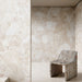 Interior featuring Riad Blanco Sassi Terrazzo Stone 60x60cm stone-effect wall and floor tiles, showcasing soft cream and beige tones with natural stone-inspired detailing, paired with a sculptural stone chair for a minimalist design.
