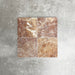 Four Fayrouz Rosso 15.2x15.2cm natural marble tiles with a tumbled finish arranged together, showcasing warm red tones, distinctive veining and natural variation against a neutral textured background.