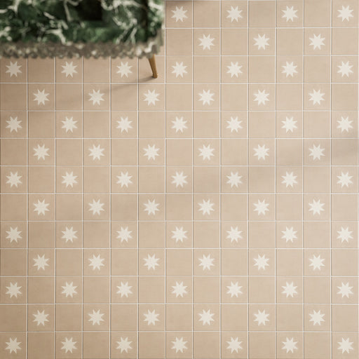 Close-up of Rubins Gold Base MINI 15x15cm Moroccan-style porcelain floor tiles, featuring warm sandy beige tones in a square grid layout, paired with white star-patterned decor tiles, natural greenery and brass accents.