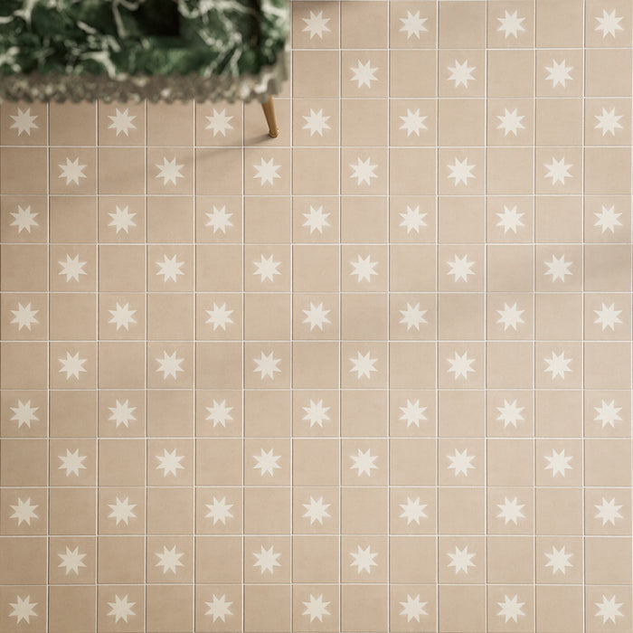 Close-up of Rubins Gold Decor MINI 15x15cm Moroccan-style porcelain floor tiles, featuring warm sandy beige tones and white eight-pointed star motifs in a repeating geometric pattern, paired with natural greenery and brass accents.