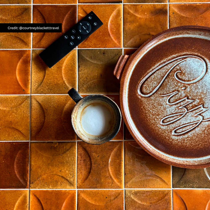 Close-up of Saigon Amber Decor Square 10cm x 10cm Moroccan style wall tiles, showcasing rich amber tones, a geometric relief pattern and handcrafted character, styled with ceramic tableware and everyday home accessories.