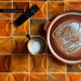 Close-up of Saigon Amber Decor Square 10cm x 10cm Moroccan style wall tiles, showcasing rich amber tones, a geometric relief pattern and handcrafted character, styled with ceramic tableware and everyday home accessories.