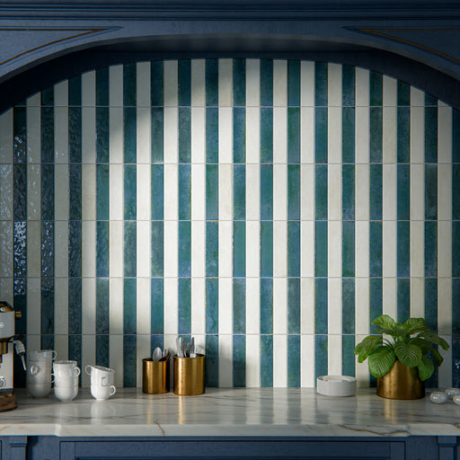 Kitchen interior featuring Allegra Blue 6x25cm gloss brick tiles, installed vertically within a statement alcove, showcasing rich blue tones with a reflective glazed finish, styled with deep blue cabinetry, brass accents, and a marble-effect worktop for a bold yet elegant design.