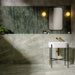 Bathroom interior featuring Petra Verde Green Stone marble style 60x120cm tiles, installed across walls and floor, showcasing soft green veining and natural stone-inspired movement, styled with brass fittings and modern basin.