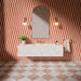 Puzzle Coral Brick Rectified 5x20cm wall and floor tiles in a vertical stacked layout, featuring warm coral and white tones in a contemporary bathroom setting with terrazzo vanity and brass fixtures.