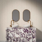 Puzzle White Brick Rectified 5x20cm porcelain tiles styled in a classic herringbone layout, creating a clean and timeless bathroom backdrop. The soft white tone and subtle surface variation add gentle depth while maintaining a crisp, contemporary feel. Paired with brushed brass fittings and a bold marble-effect vanity, the slim brick format enhances texture and pattern, making it ideal for elegant bathroom walls or refined feature areas.