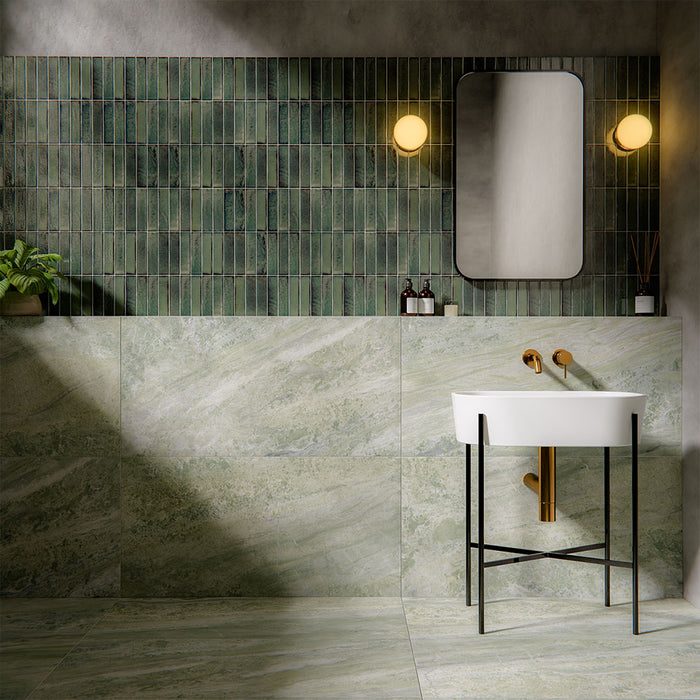 Bathroom interior featuring Puzzle Forest Green Brick rectified wall and floor tiles in 5x20cm format, installed vertically as a textured feature wall above large-format marble-effect tiles, styled with brass fittings and modern basin.