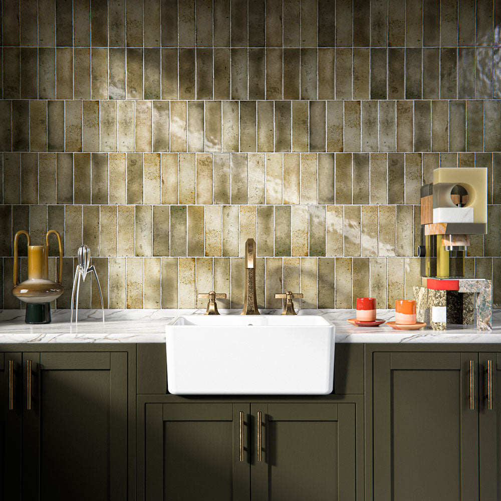 Kitchen interior featuring Foundry Bricks Moss Green 6.5x20cm ceramic wall tiles, arranged in a stacked layout with tonal variation, styled with a farmhouse sink, marble-effect worktop, and brass fittings.