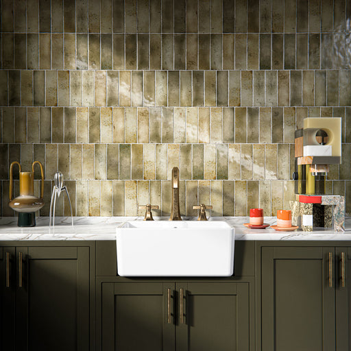 Kitchen interior featuring Foundry Bricks Moss Green 6.5x20cm ceramic wall tiles, arranged in a stacked layout with tonal variation, styled with a farmhouse sink, marble-effect worktop, and brass fittings.