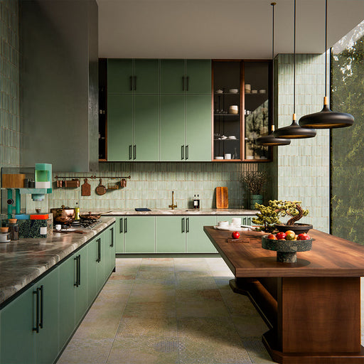 Puzzle Sage Green Brick Rectified 5x20cm porcelain tiles used as a full-height kitchen splashback, showcasing soft sage green tones with subtle speckling and natural shade variation. The slim brick format enhances vertical lines and texture, pairing beautifully with matching cabinetry, warm wood finishes and brass accents for a cohesive, contemporary kitchen design.