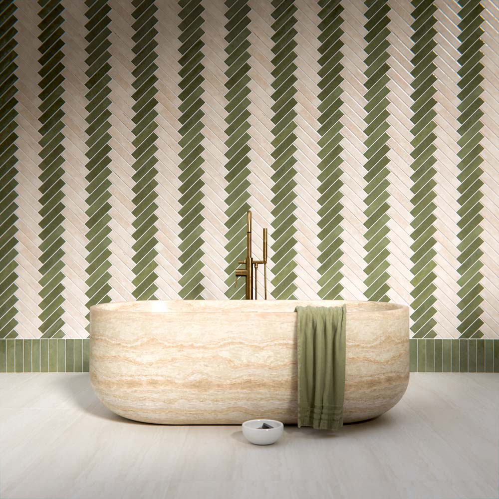 Bathroom interior featuring Nomad Sage Green and Nomad Oatmeal 6 x 24.6cm industrial style brick tiles, arranged in a striking herringbone pattern to create a layered, textural wall design, paired with a natural stone bath and soft neutral flooring for a calm, contemporary finish.