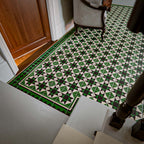 Greenbrook Manor side/border 20cm x 20cm porcelain tiles installed in a hallway, featuring a green, black and white Victorian-style geometric border framing the patterned floor tiles near a doorway.