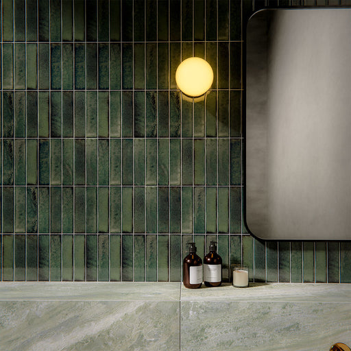 Bathroom interior featuring Puzzle Forest Green Brick rectified wall and floor tiles in 5x20cm format, installed vertically as a textured feature wall above large-format marble-effect tiles, styled with brass fittings and modern basin.