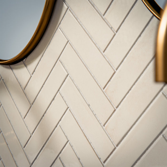 Puzzle White Brick Rectified 5x20cm porcelain tiles styled in a classic herringbone layout, creating a clean and timeless bathroom backdrop. The soft white tone and subtle surface variation add gentle depth while maintaining a crisp, contemporary feel. Paired with brushed brass fittings and a bold marble-effect vanity, the slim brick format enhances texture and pattern, making it ideal for elegant bathroom walls or refined feature areas.