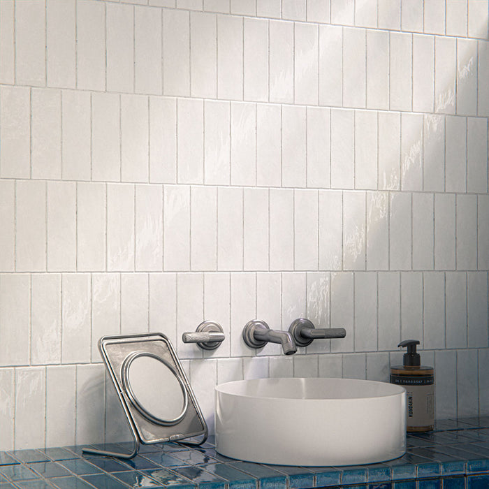 Bathroom interior featuring Foundry Bricks Arctic White 6.5x20cm ceramic wall tiles in a horizontal layout, styled with a blue tiled vanity, countertop basin and brushed metal fixtures.